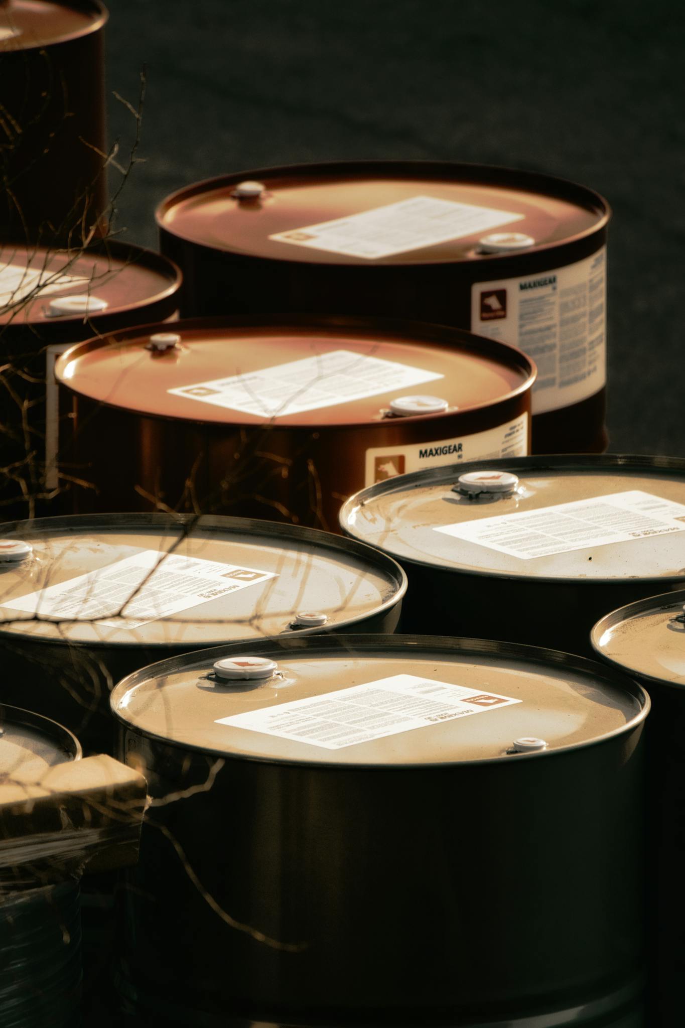 Multiple red and silver steel barrels arranged outdoors for industrial storage.